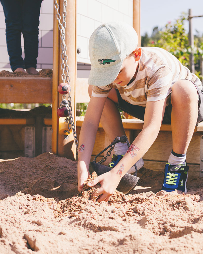 Ein kleiner Junge spielt auf einem Spielplatz im Sand.